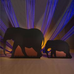 two elephants standing next to each other in front of a purple background with light streaks