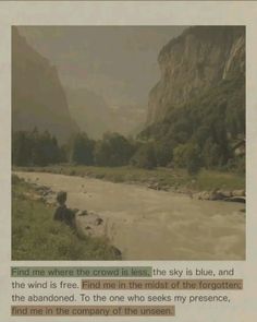 an image of a person sitting on the bank of a river with mountains in the background