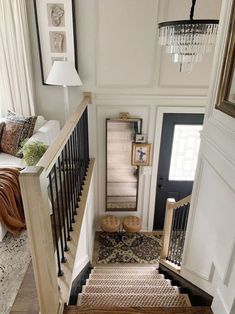 an overhead view of a staircase leading to a living room and dining room with white walls