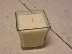 a candle sitting on top of a wooden table next to a glass container filled with liquid