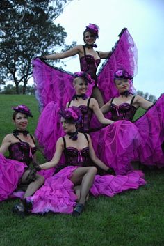 a group of women in purple dresses sitting on the grass