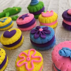 there are many decorated donuts on the table and one is pink, blue, yellow and purple