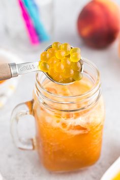 a spoon full of jelly sitting on top of a jar filled with oranges and peaches