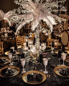 a table set with black and white plates, silverware and centerpieces for an elegant event