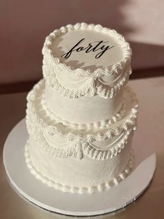 a three tiered white cake with the word forty on it