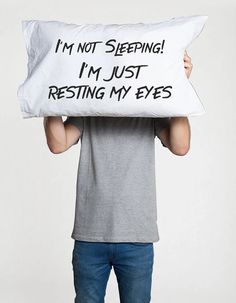 a man holding a pillow that says i'm not sleeping, i'm just resting my eyes