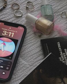 a cell phone sitting on top of a table next to some jewelry and a book