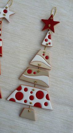 three christmas tree ornaments are hanging on a table with red and white polka dot decorations