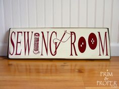 a wooden sign that says sewing room with yarn and buttons on it, sitting on a hard wood floor