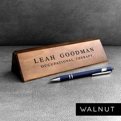 a pen sitting on top of a desk next to a plaque that says, leah goodman