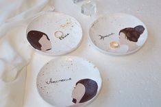 three plates with different designs on them sitting on a white tablecloth next to a diamond