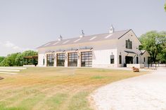 a large white barn sitting on top of a lush green field