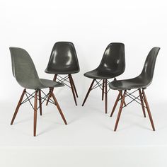 three black chairs with wooden legs on a white background and one has a gray seat