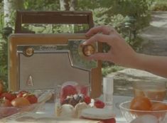 a person holding a radio on top of a table filled with fruits and vegetables next to other food items