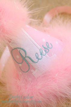 a pink teddy bear with a name on it's hat and some fluffy fur