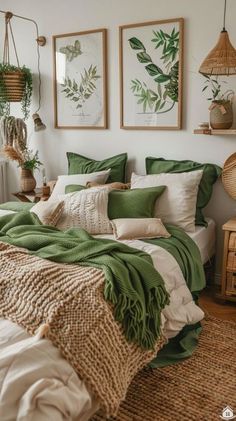 a bed covered in green and white blankets next to two pictures hanging on the wall