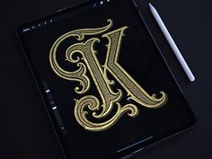 a tablet with a gold letter k on it and a white pen next to it