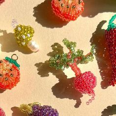 several beaded fruits and vegetables are arranged on a table with shadows from the sun