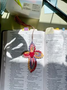 an open book with a crocheted cross on it