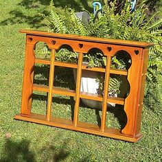 a wooden shelf sitting on top of a lush green grass covered field next to a bush