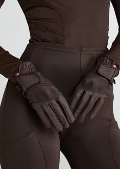 a woman wearing brown leather gloves with her hands on her hip and the back of her body