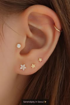 an ear with three stars and two moon piercings on it's sides, one is