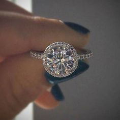 a woman's hand holding an engagement ring with diamonds on the middle and sides