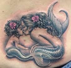 a woman's stomach with a tattoo of two mermaids kissing on the belly