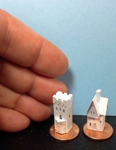 two tiny houses are on top of one coin and the other is being held up by a hand