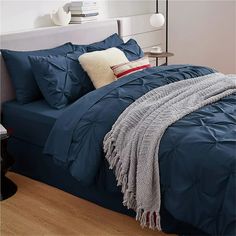 a bed with blue comforter and pillows on it in a bedroom area next to a lamp