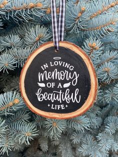 a wooden ornament hanging from a tree with the words in loving memory of a beautiful life