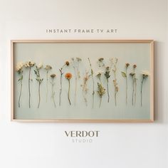 the frame is hanging on the wall with dried flowers in it and an inscription that reads instant frame tv art