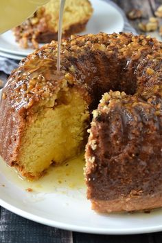 a bundt cake being cut with a knife on a white plate and another piece has been eaten