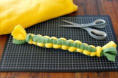 a yellow and green caterpillar sitting on top of a cutting board next to scissors