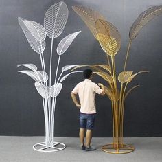 a man standing next to a tall metal plant