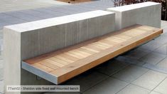 a wooden bench sitting on the side of a cement wall next to a planter