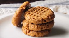 three peanut butter cookies stacked on top of each other in front of a white plate