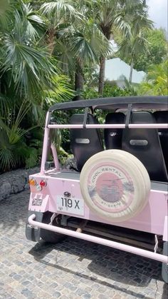 a pink jeep parked in front of some palm trees