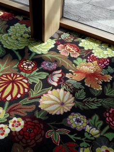 an area rug with flowers on it next to a glass door that has a wooden frame