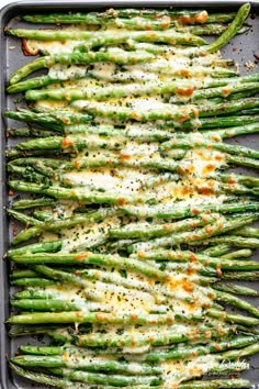 asparagus covered in melted cheese on a baking sheet