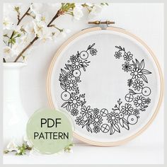 a cross stitch pattern with flowers on it and a vase full of flowers in the background