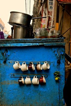 an old blue stove with cups hanging on it's side