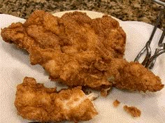 two fried chicken pieces on a plate with tongs