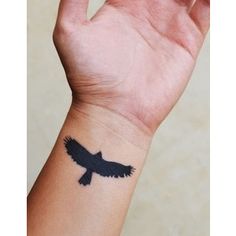 a hand with a black bird tattoo on it's left arm and the wrist