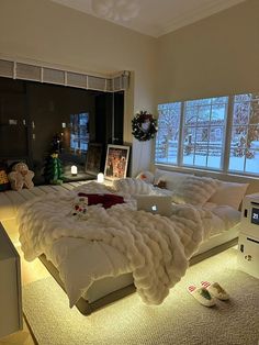 a large bed sitting in the middle of a living room next to two windows with christmas decorations on them