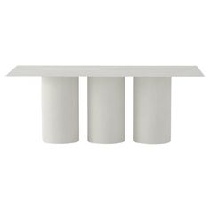 three white cylinders are sitting on top of a table with one column in the middle