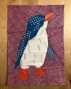 a quilted piece of fabric with a small penguin on it's face and legs