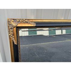 a large gold framed mirror sitting on top of a black floor