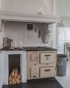 an old fashioned stove in the middle of a kitchen with logs stacked on it's sides