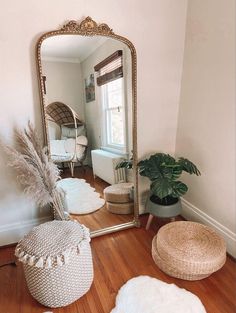 a mirror sitting on top of a wooden floor next to a chair and potted plant